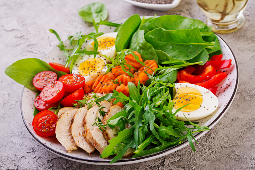 Plate with Keto diet food, Cherry tomatoes, chicken breast, eggs , carrot, salad, with arugula and spinach. Keto lunch