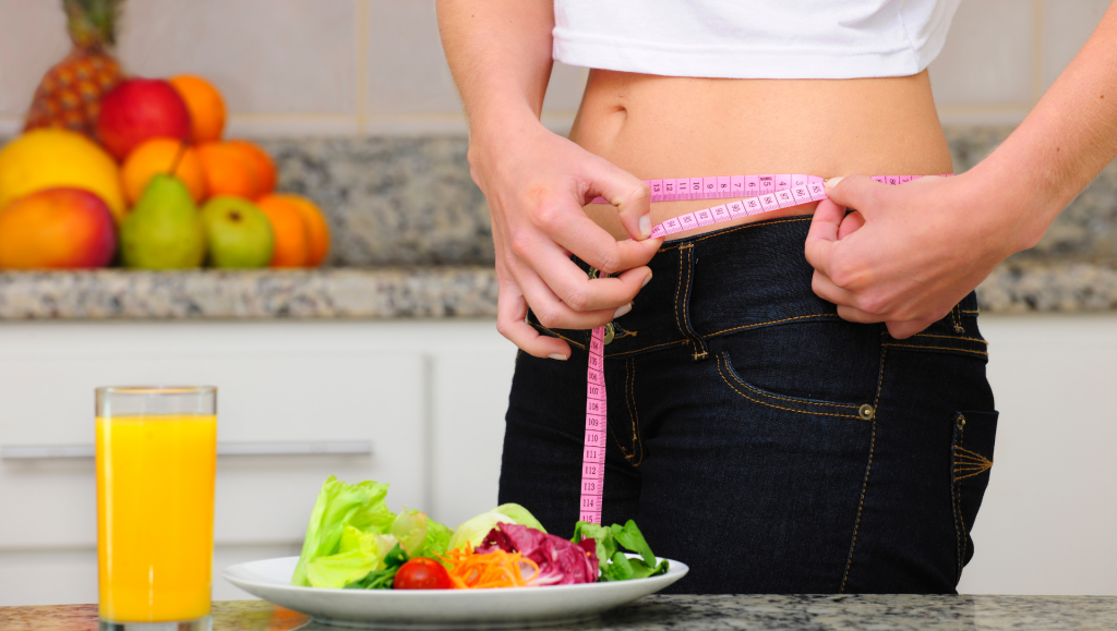 Diet: woman with salad and measuring tape