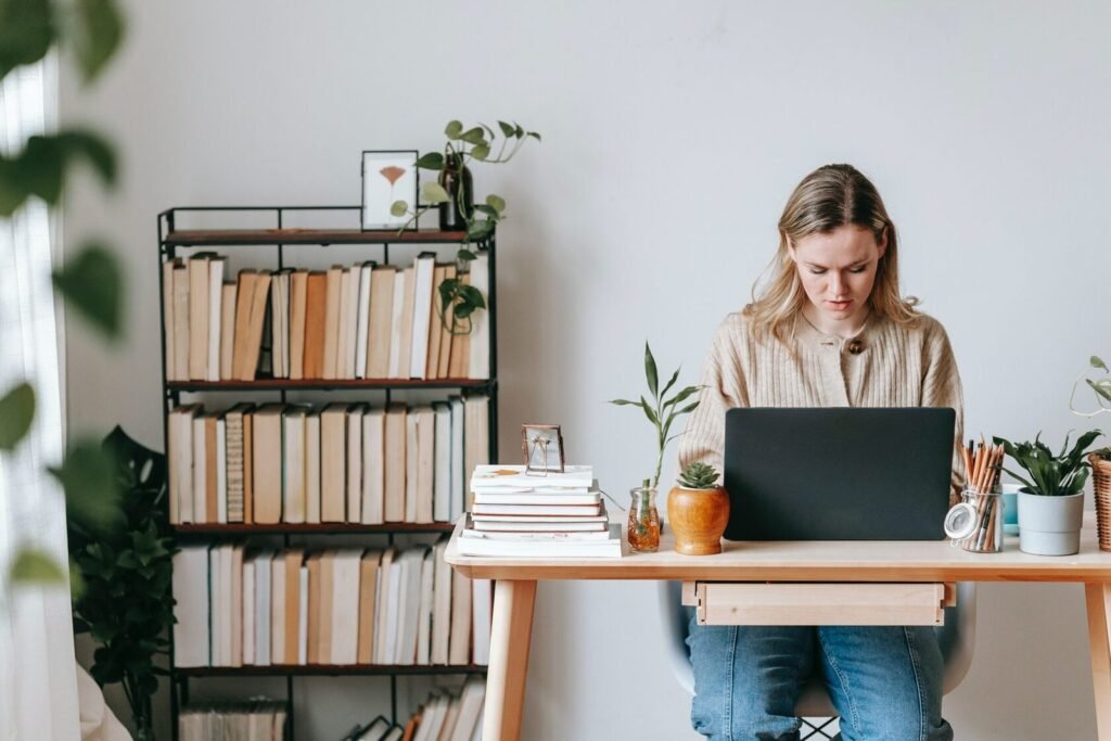 Woman studying naturopathy online in Australia using a laptop surrounded by plants and herbal books, representing accredited online naturopathy courses from International College of Naturopathic Science